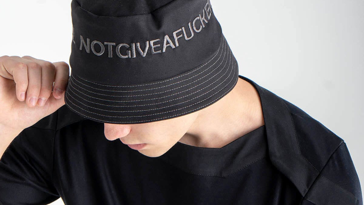 Person wearing a black bucket hat with text on a white background

